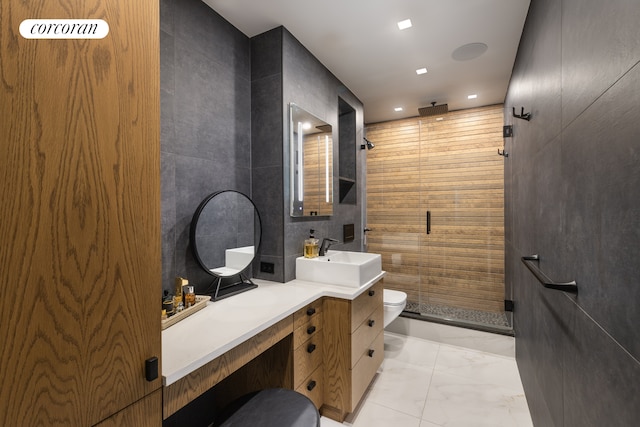 bathroom with a stall shower, toilet, marble finish floor, vanity, and tile walls