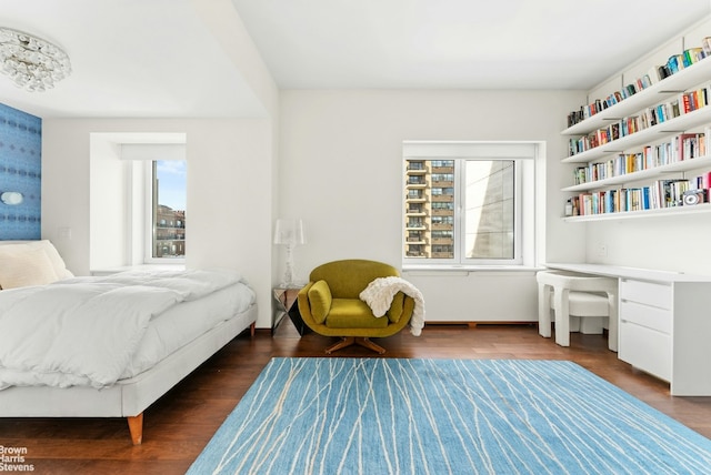 bedroom with dark hardwood / wood-style flooring, built in desk, and multiple windows