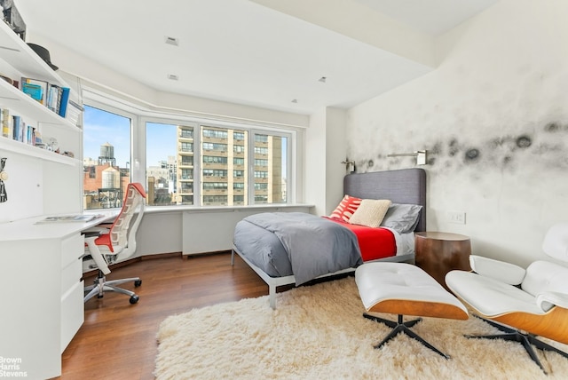 bedroom with multiple windows, built in desk, and dark hardwood / wood-style floors