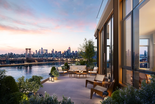 patio terrace at dusk featuring a water view, a view of city, and an outdoor hangout area