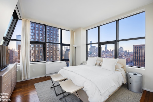 bedroom with a view of city, baseboards, and wood finished floors