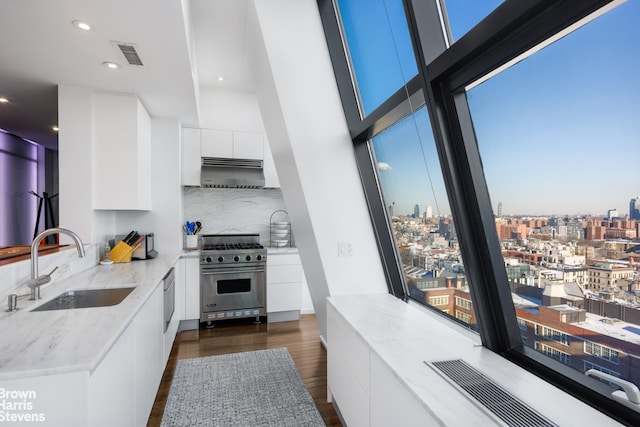 kitchen with visible vents, modern cabinets, high end stainless steel range, under cabinet range hood, and a sink