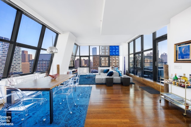 living room with a view of city, a healthy amount of sunlight, wood finished floors, and floor to ceiling windows