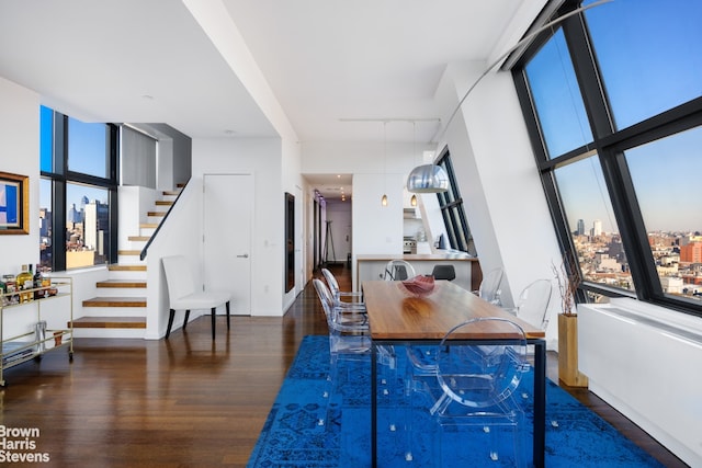 dining area with stairs, wood finished floors, a city view, and a healthy amount of sunlight