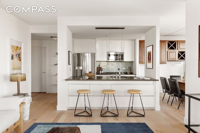 kitchen with sink, white cabinetry, appliances with stainless steel finishes, a kitchen breakfast bar, and kitchen peninsula