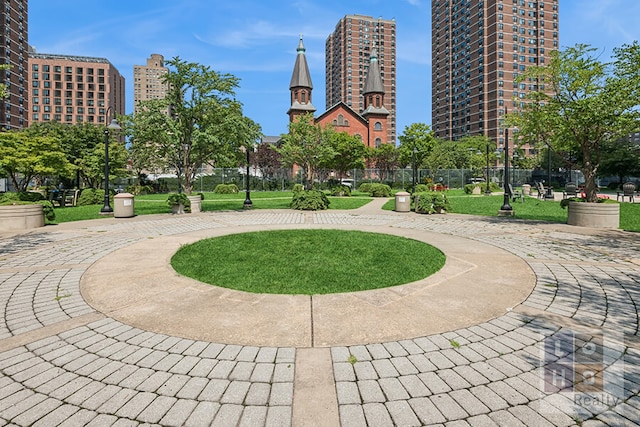 view of home's community with fence, a lawn, and a city view