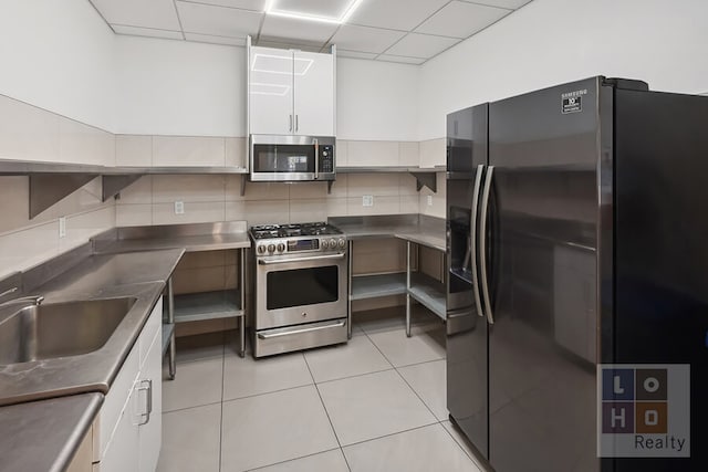 kitchen with light tile patterned floors, stainless steel appliances, tasteful backsplash, stainless steel counters, and white cabinetry