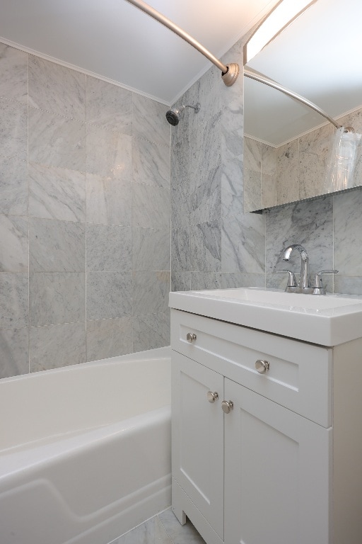 bathroom with vanity, tiled shower / bath combo, decorative backsplash, and tile walls