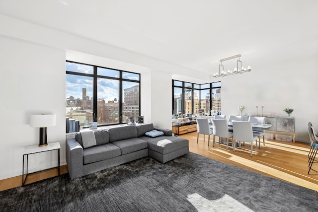 living room featuring a view of city, wood finished floors, a wealth of natural light, and a notable chandelier