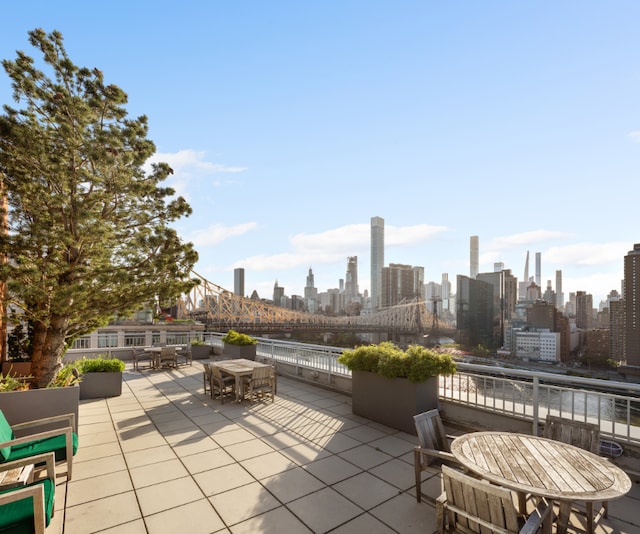 view of patio with a water view, a view of city, and outdoor dining space