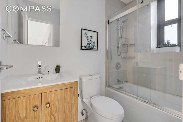 bathroom featuring enclosed tub / shower combo, toilet, and vanity