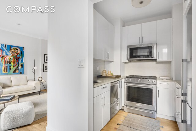 kitchen with open floor plan, light countertops, appliances with stainless steel finishes, and light wood-type flooring