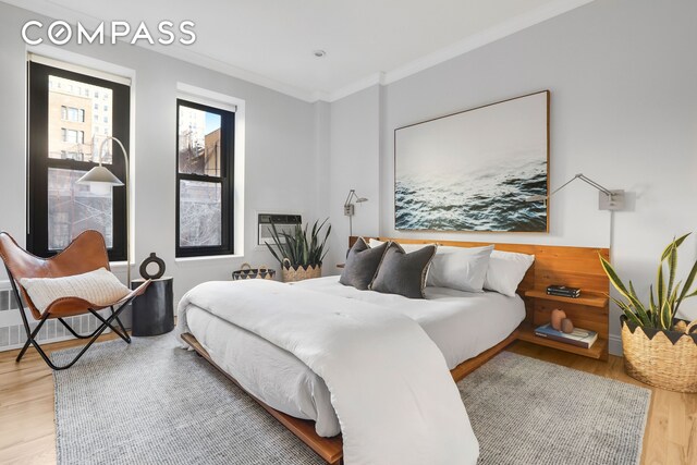 bedroom with wood finished floors and crown molding