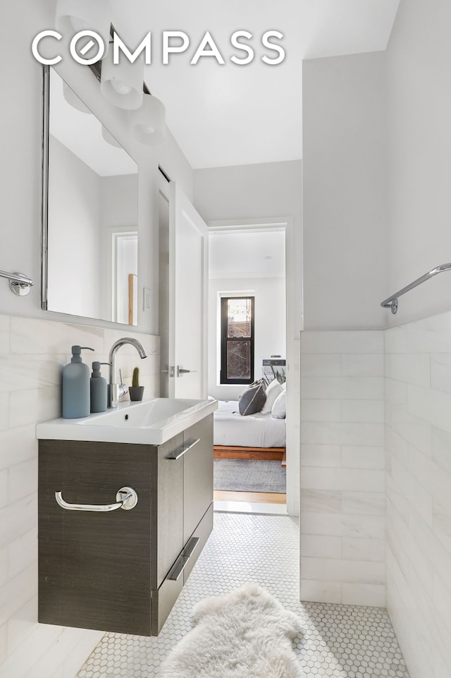 ensuite bathroom featuring tile patterned floors, ensuite bath, tile walls, tiled shower, and vanity