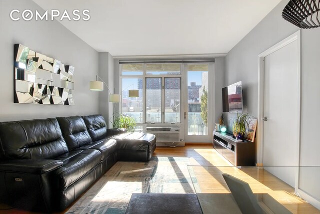 living room featuring a wall mounted air conditioner, expansive windows, and light wood-type flooring