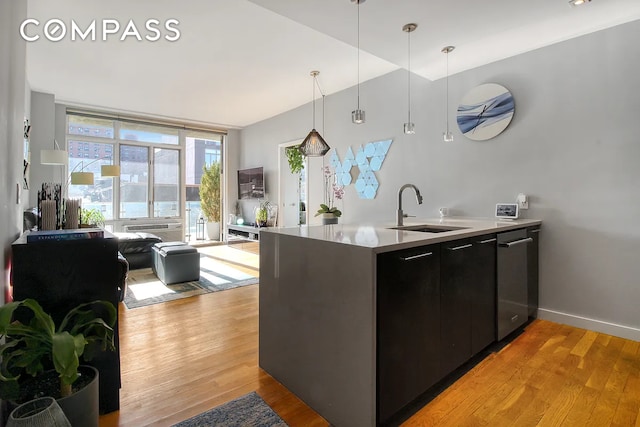 kitchen featuring a sink, modern cabinets, dark cabinetry, decorative light fixtures, and dishwasher
