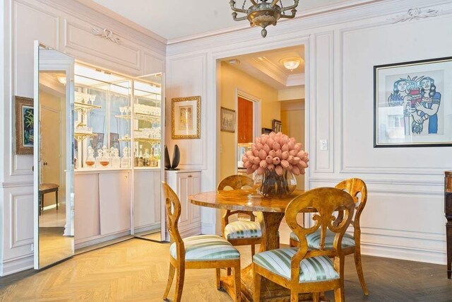 dining area featuring an inviting chandelier, crown molding, and dark parquet floors