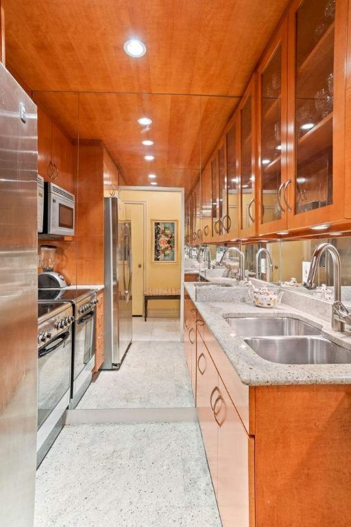 kitchen featuring stainless steel appliances, sink, wood ceiling, and light stone counters