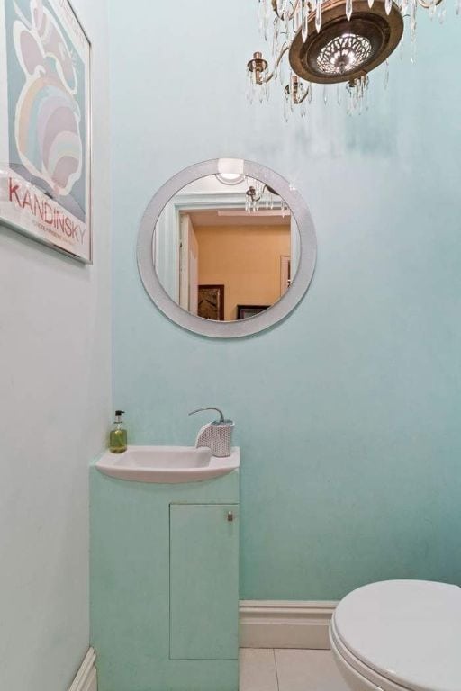 bathroom with toilet, sink, a chandelier, and tile patterned flooring