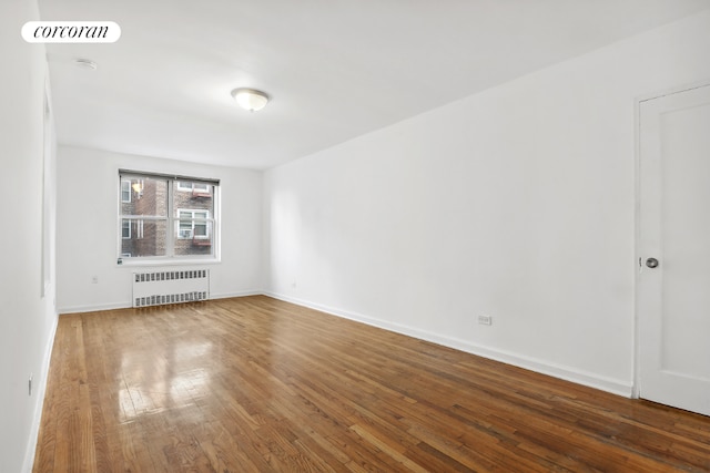 unfurnished room featuring radiator and hardwood / wood-style flooring