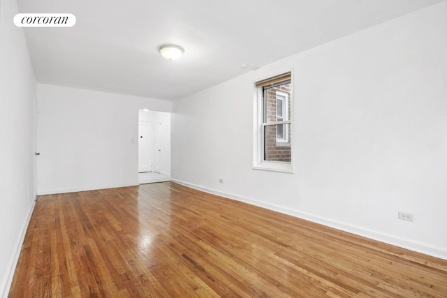 unfurnished room featuring hardwood / wood-style floors, visible vents, and baseboards