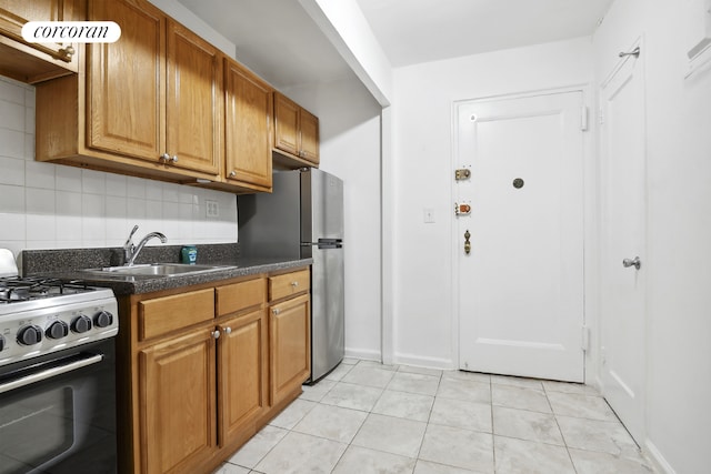 kitchen featuring stainless steel appliances, tasteful backsplash, sink, and light tile patterned flooring