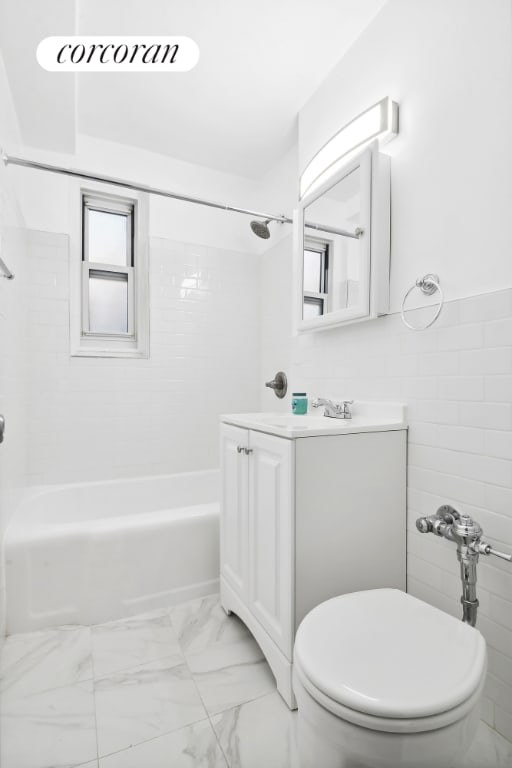 full bathroom featuring tile walls, vanity, tiled shower / bath, and toilet