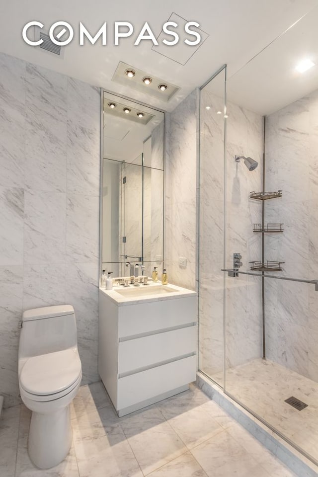 bathroom featuring toilet, marble finish floor, a walk in shower, and vanity