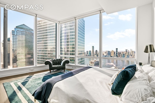 bedroom with a view of city, wood finished floors, and floor to ceiling windows