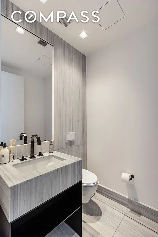 bathroom featuring vanity, toilet, and baseboards