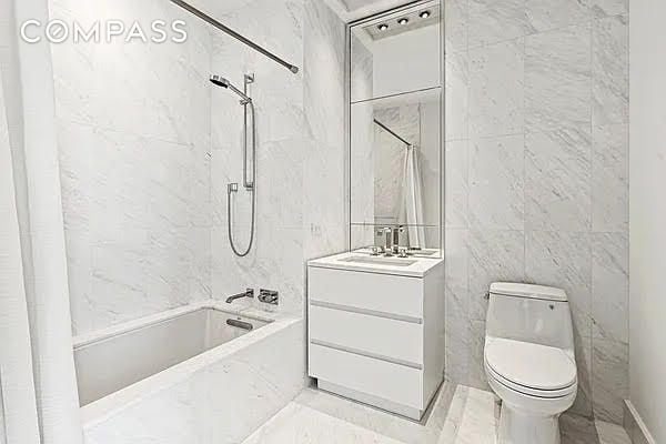 full bathroom featuring shower / tub combo, tile walls, vanity, and toilet