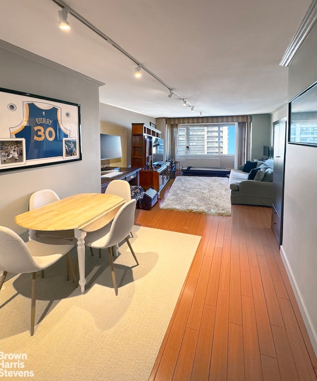 dining space with hardwood / wood-style flooring and track lighting