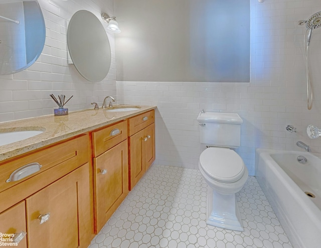 bathroom with double vanity, a sink, shower / washtub combination, tile walls, and toilet