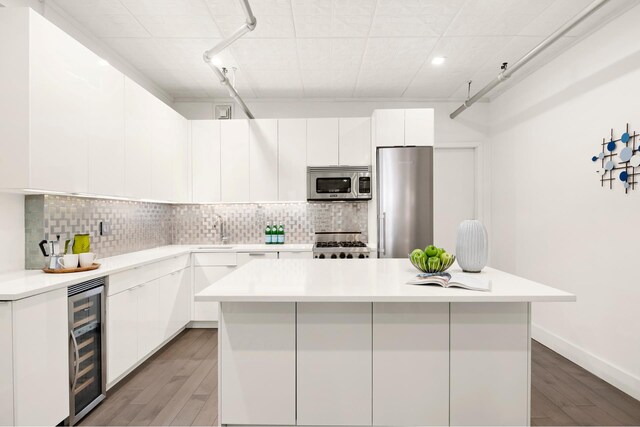 kitchen featuring wine cooler, stainless steel appliances, and white cabinets