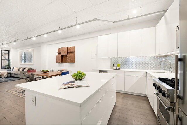 kitchen featuring a kitchen island, white cabinetry, sink, high end range, and light hardwood / wood-style flooring