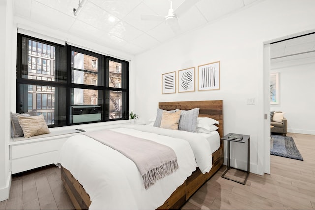 bedroom with a ceiling fan, wood finished floors, and baseboards