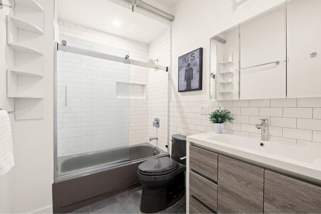 full bathroom with toilet, tile walls, vanity, enclosed tub / shower combo, and decorative backsplash