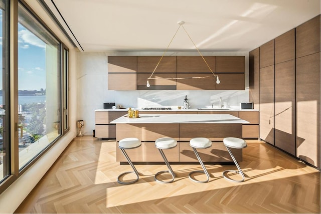 kitchen with sink, a kitchen island, light parquet flooring, and a kitchen bar