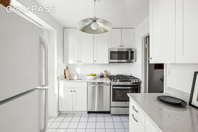 kitchen featuring sink, white cabinetry, stainless steel appliances, light stone countertops, and light tile patterned flooring