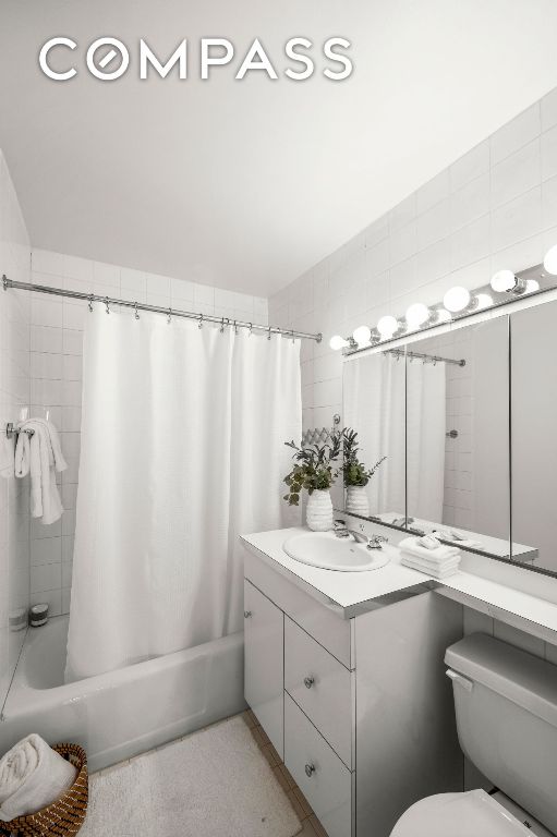 full bathroom featuring shower / bathtub combination with curtain, vanity, tile walls, and toilet