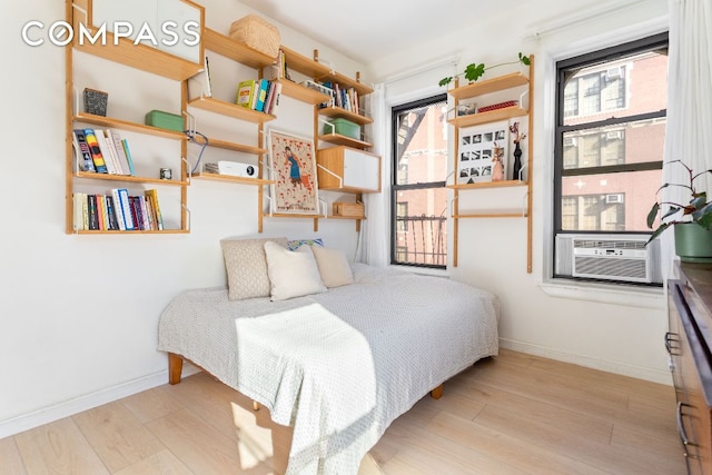 bedroom featuring light wood-type flooring, cooling unit, and baseboards