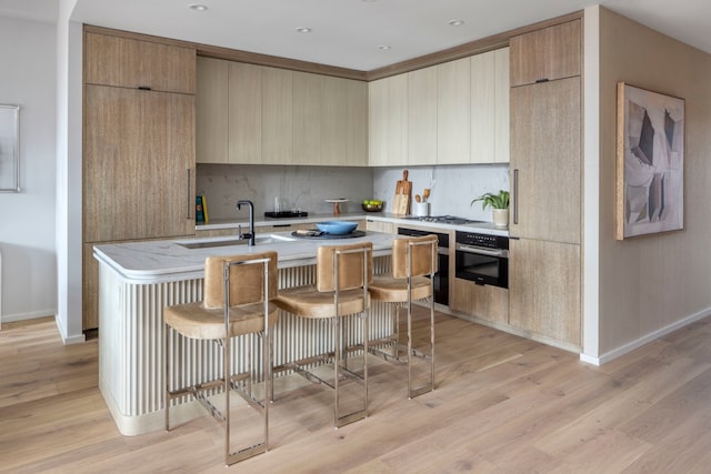 kitchen with wall oven, an island with sink, modern cabinets, and decorative backsplash