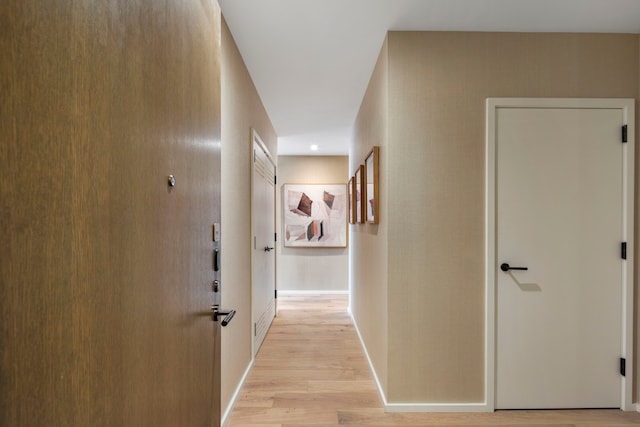 corridor with baseboards and light wood-style flooring