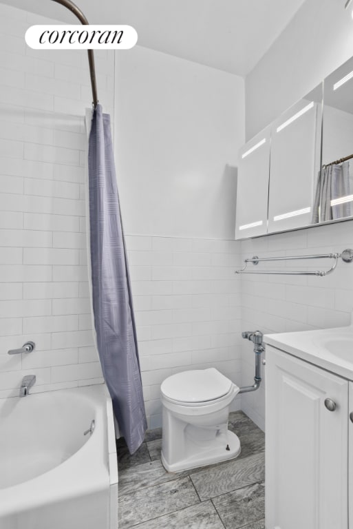 full bathroom with vanity, tile walls, shower / tub combo with curtain, and toilet