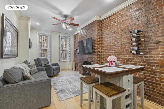 living area featuring light wood-style floors, brick wall, crown molding, and a ceiling fan