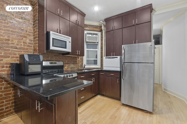 kitchen with a sink, stainless steel appliances, a wall mounted air conditioner, crown molding, and light wood-type flooring