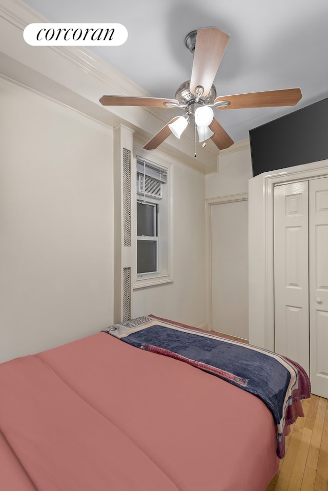 bedroom with ceiling fan, a closet, wood finished floors, and crown molding