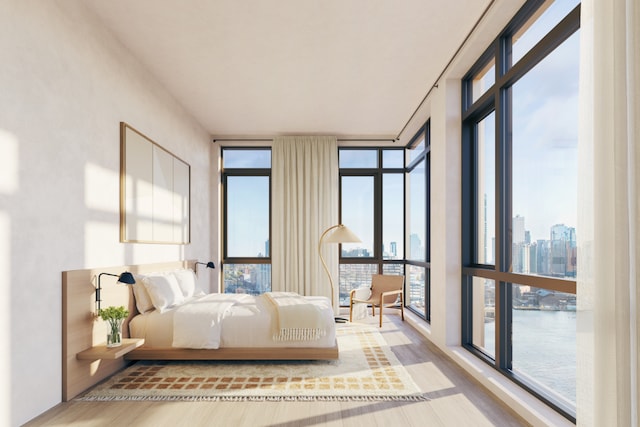 bedroom featuring expansive windows, a water view, and hardwood / wood-style floors