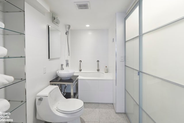 bathroom featuring toilet, recessed lighting, visible vents, tile walls, and tiled tub