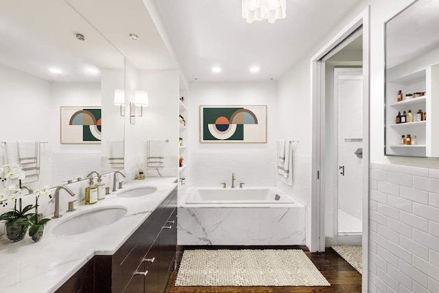 bathroom with shower with separate bathtub, built in features, tile walls, hardwood / wood-style flooring, and vanity